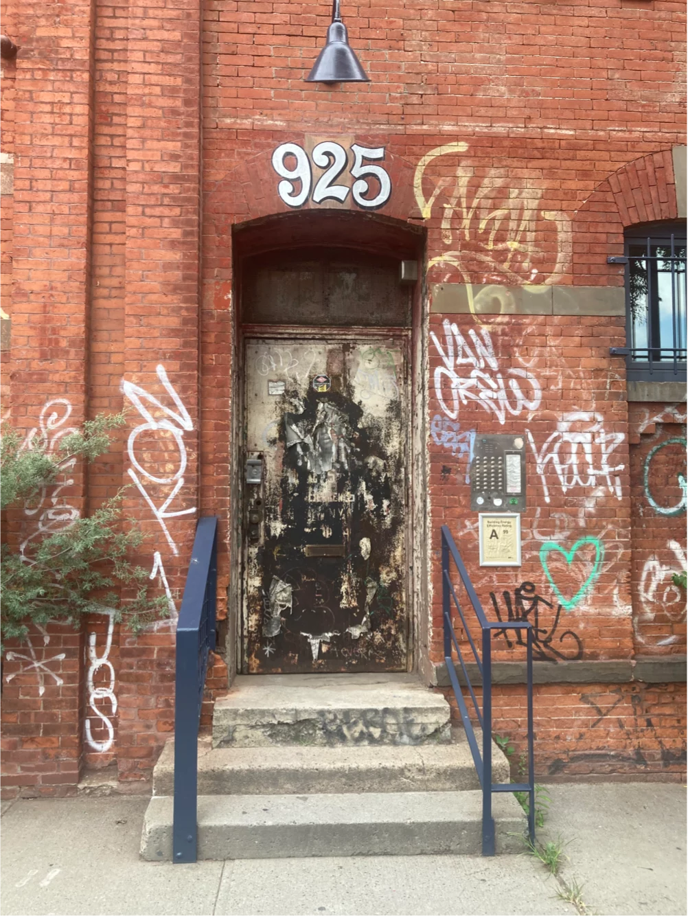 A door with the numbers 925 painting above it on a red brick building
